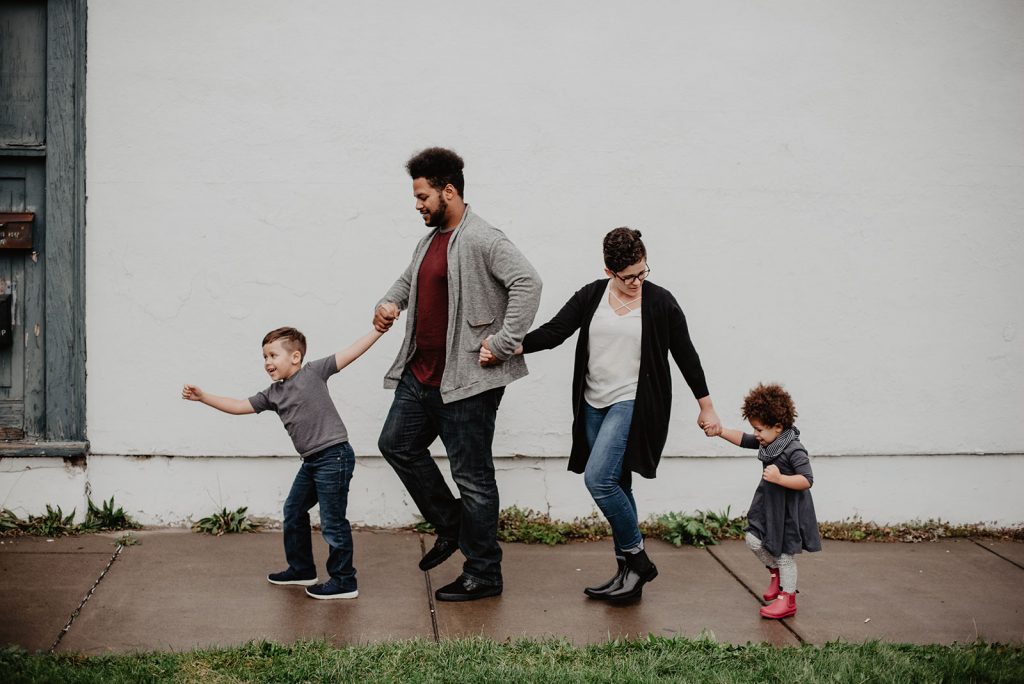 young husband and wife holding hands with their two young children, a boy and a girl