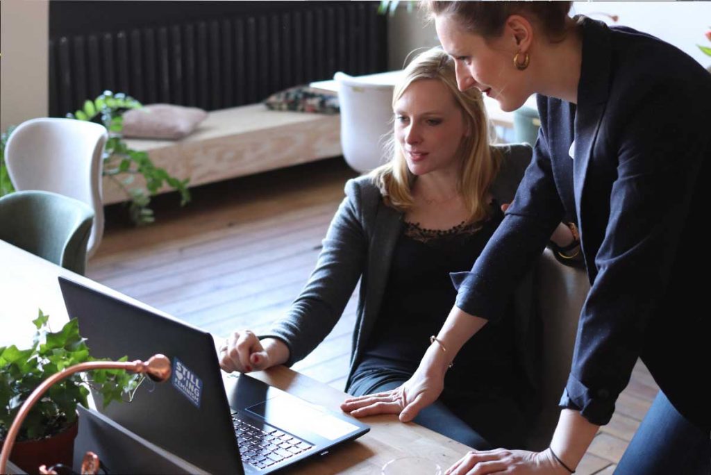 two female executives working at a laptop