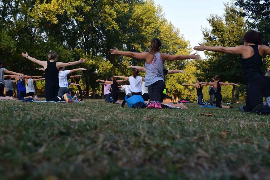 group of women wearing exercise clothing working out in a city park