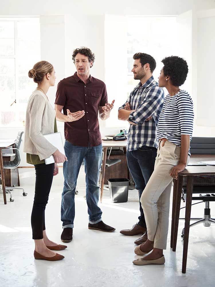 group of two male and two female coworkers standing in a circle talking