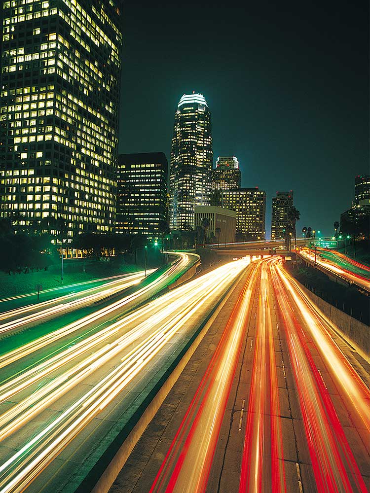 night image of illuminated highway with skyscrapers in background