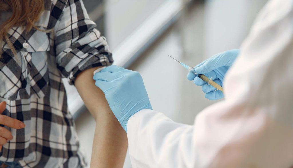 woman receiving a vaccine in her left arm