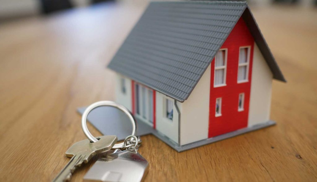 small model of a house with set of keys laying next to it