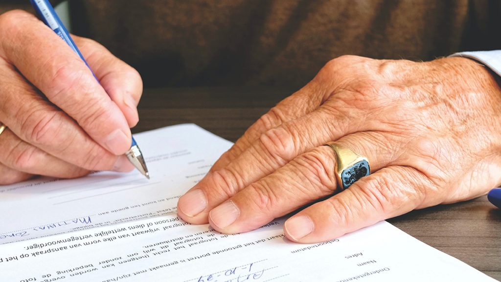 Close up view of man's hands and holding a pen as a legal document is being signed