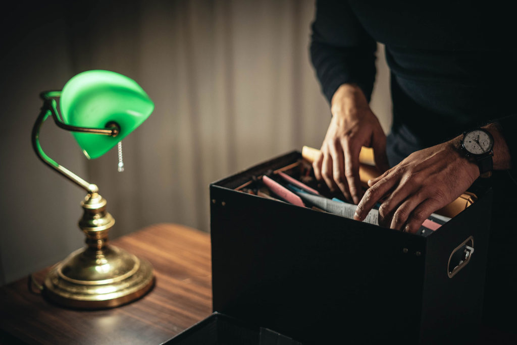 Hands rummaging through law files on lawyer desk next to desk lamp